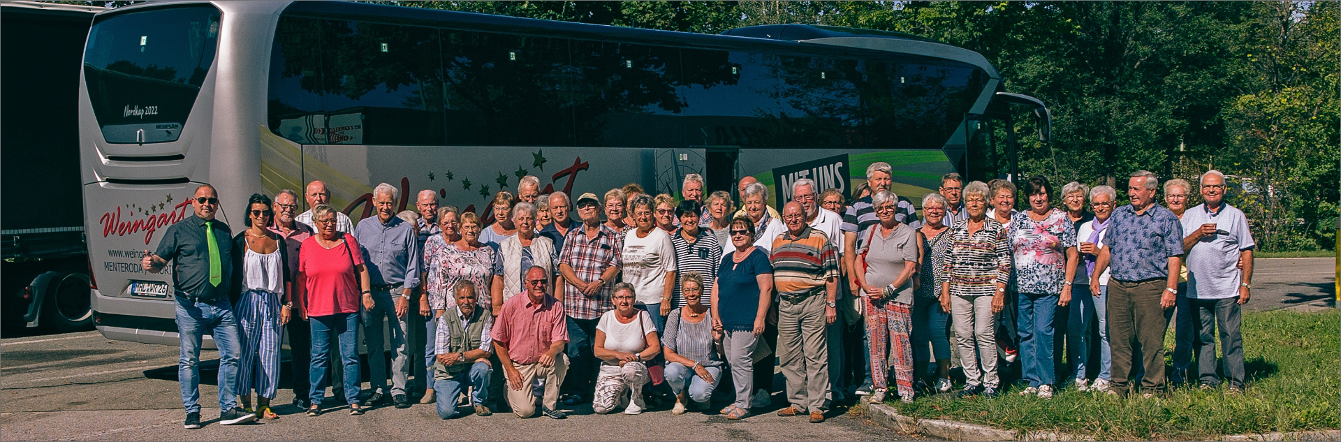 Gruppenfoto einer Rentnerreisegruppe mit Busfahrer vor einem silbernen Weingart Reisebus